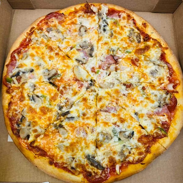 A whole Pascali's Pizza Corner pizza, topped with melted cheese, mushrooms, ham, and green peppers, in a cardboard box.