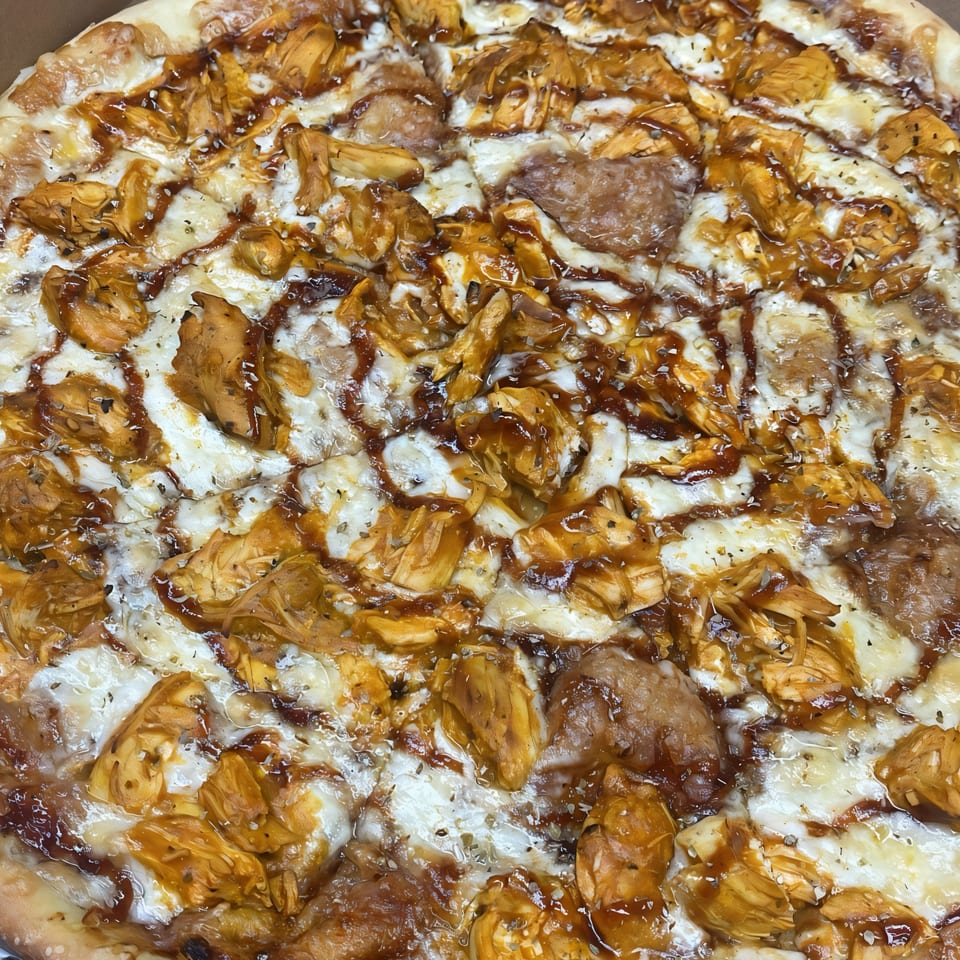 Close-up of a Pascali's Pizza Corner BBQ chicken pizza, topped with melted cheese and sauce.