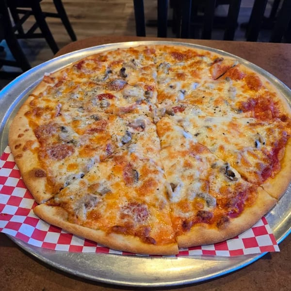 A whole Pascali's Pizza Corner pizza, cut into slices, with cheese, mushrooms, and pepperoni.