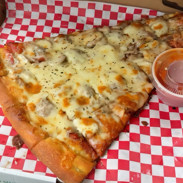 A large slice of Pascali's Pizza Corner pizza with melted cheese and toppings, in a red and white checkered box.