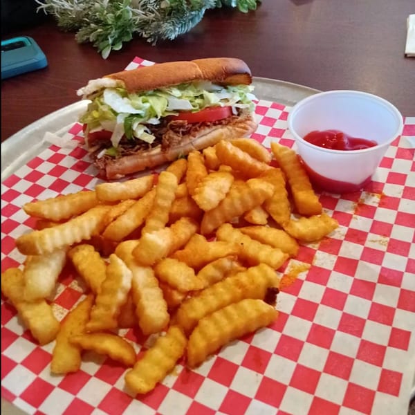 A Pascali's Pizza Corner pulled pork sub with lettuce and tomato, served with crinkle-cut fries and ketchup.